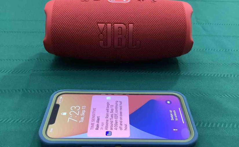Picture of an iPhone in front of the JBL Charge 5 speaker.
