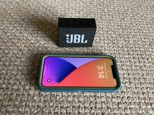 Picture of an iPhone in front of the JBL Go Bluetooth speaker. Battery Capacity mAh.