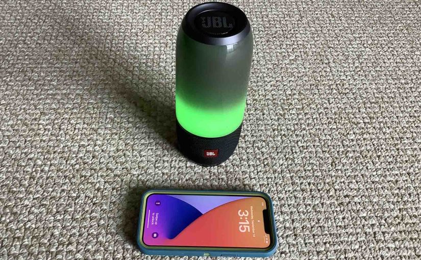 Picture of an iPhone in front of the JBL Pulse 3 light show speaker.