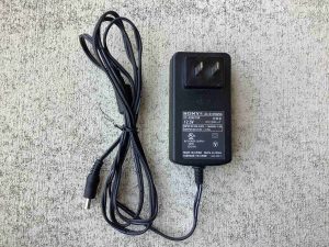 Picture of the label side of the Sony AC-S125V25A AC adapter along with the accompanying cord.